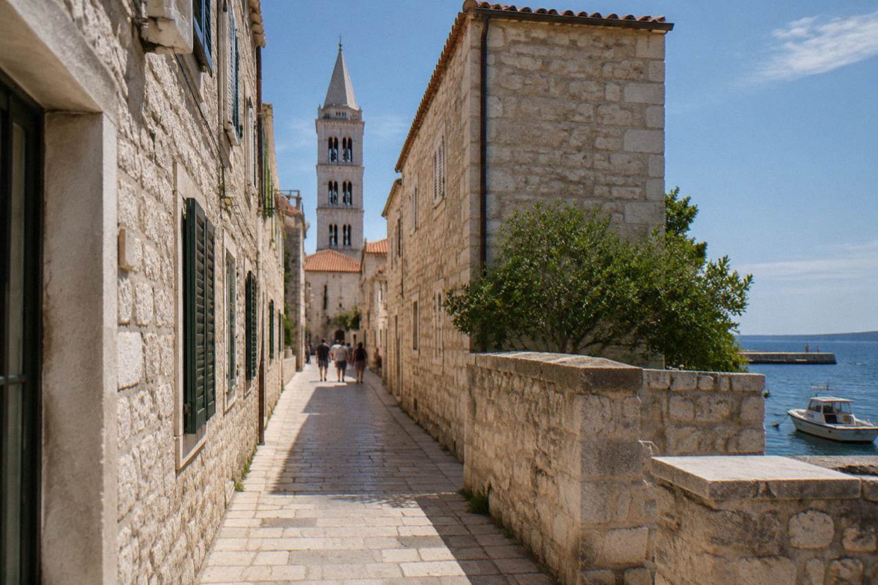 Pale Old Town lane with a bell tower at the end in midday sun