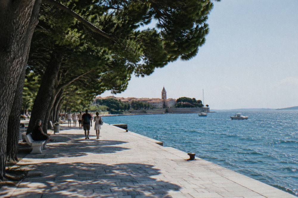 Old Town waterfront promenade with pines and sparkling sea on a clear day