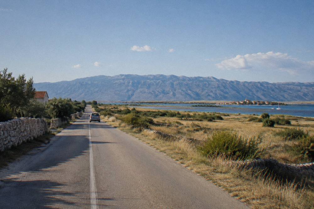 Flat road with the Velebit ridge on the horizon and glimpses of sea