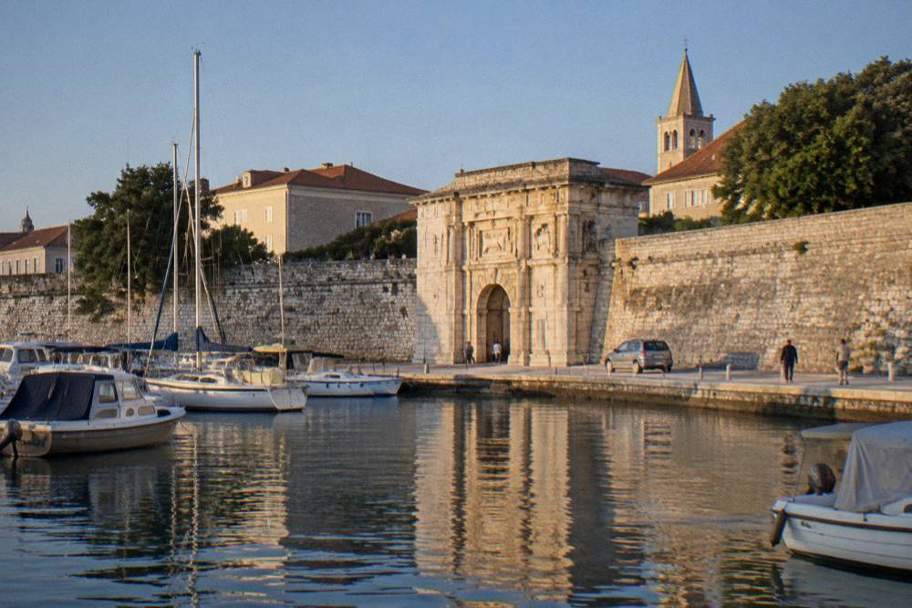 Old Town walls and gate seen from the harbour with moored boats