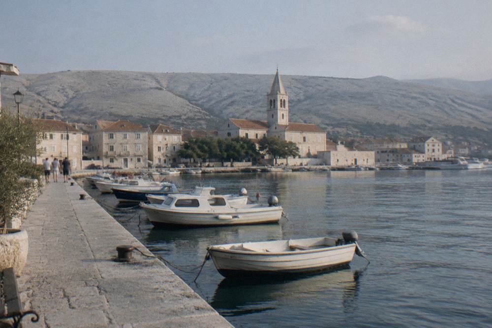 Pag Town waterfront with boats, a church tower and arid hills
