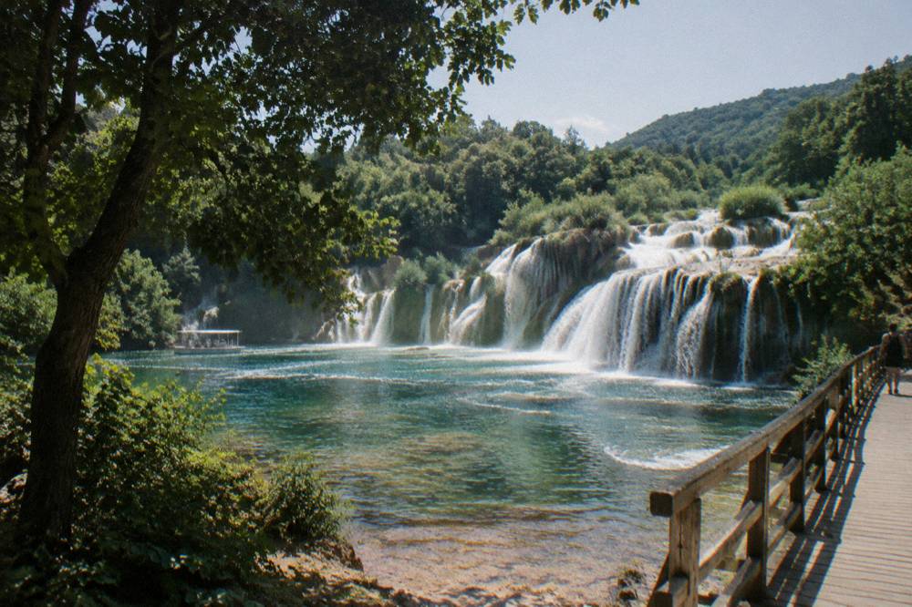 Skradinski Buk falls over travertine ledges with green pools on a clear day
