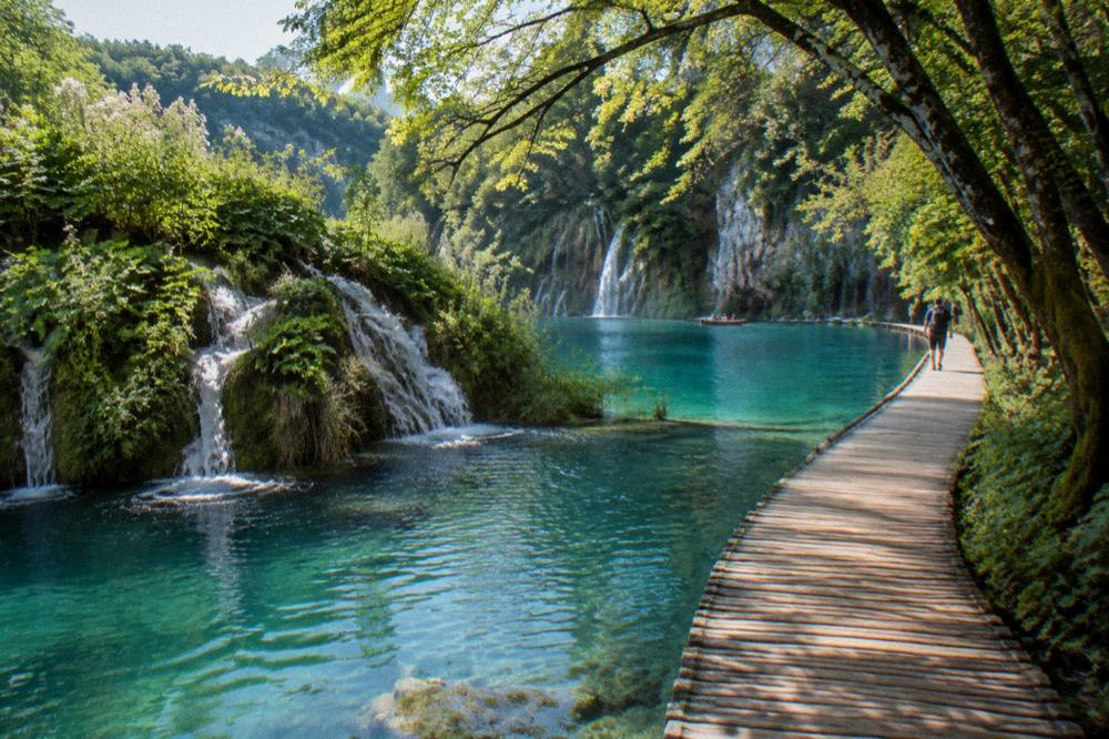 Turquoise lakes and waterfalls with a wooden boardwalk in beech forest