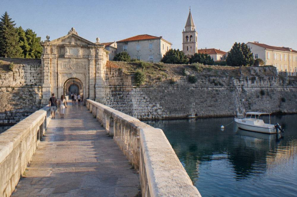 Stone footbridge leading to the Old Town gate with distant walkers