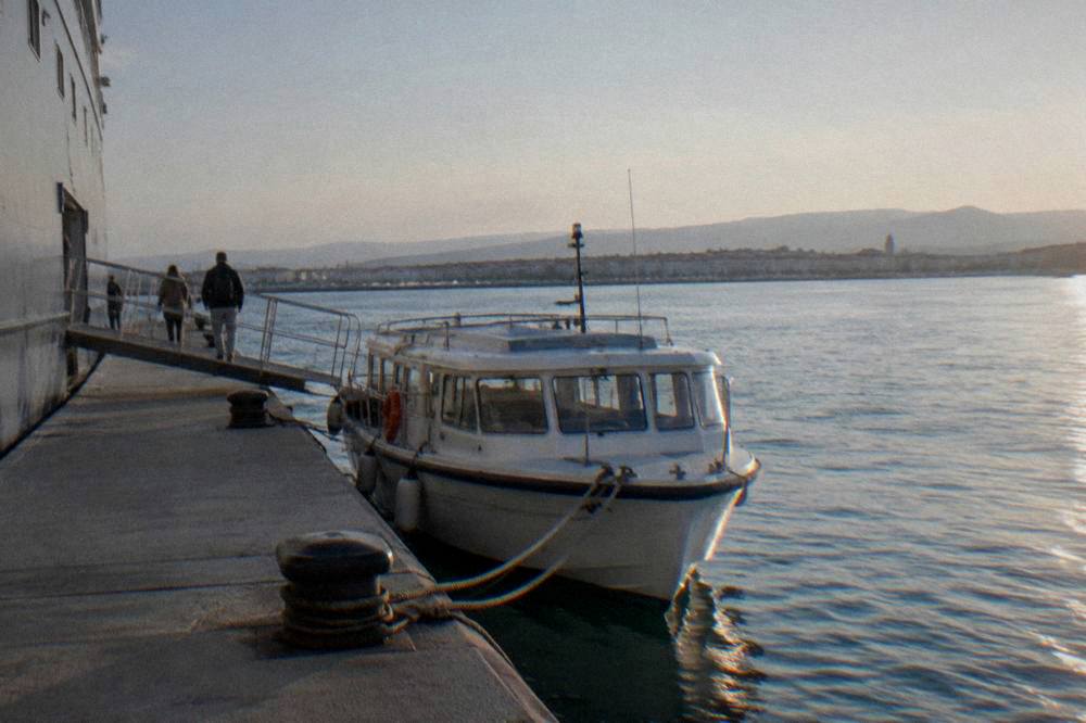 Tender boat tied at a quay in calm sea and late afternoon sun