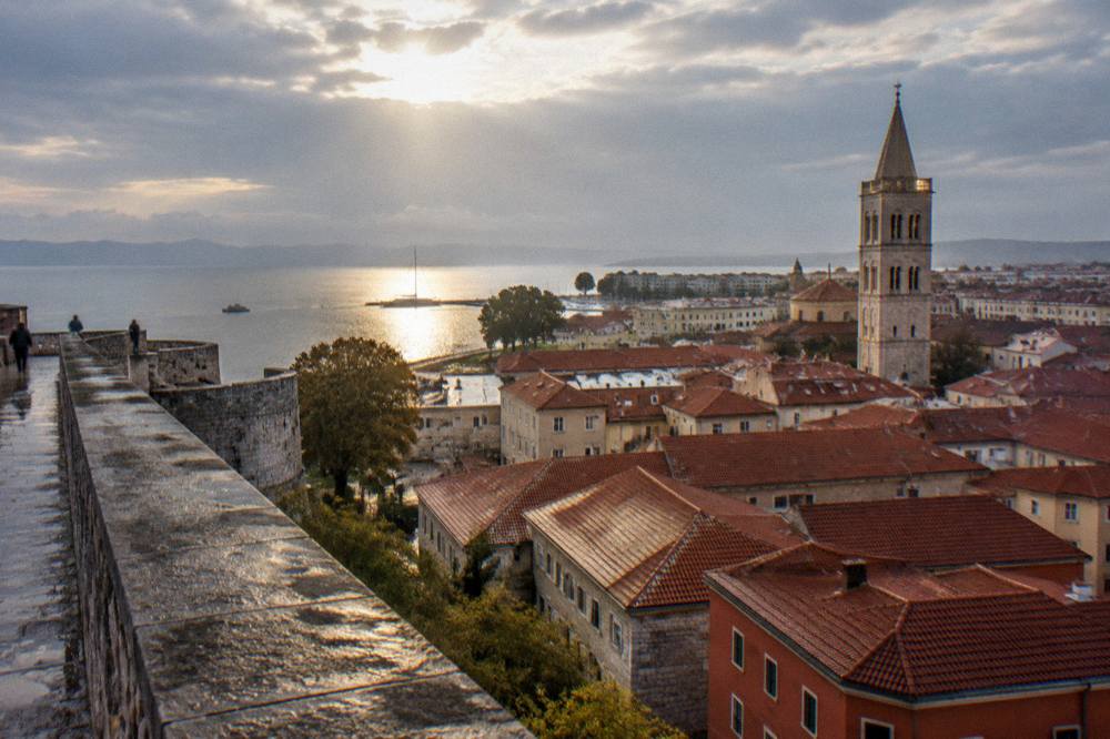 Sun breaking through clouds over wet rooftops and the bell tower