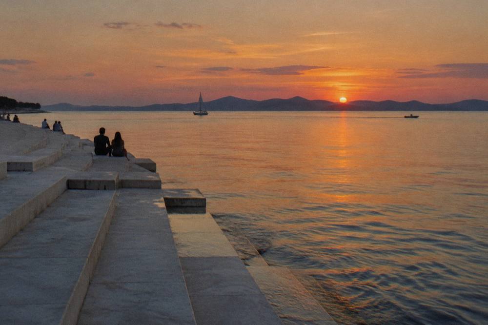 Marble steps down to calm sea at sunset with distant island ridges