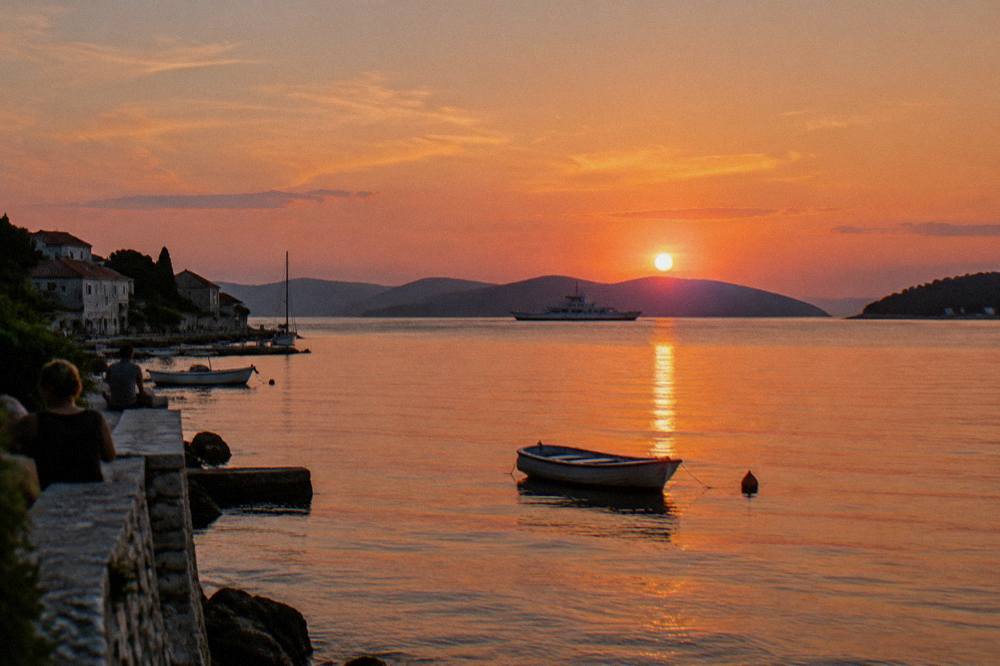 Sunset over island ridges across the channel with a ferry silhouette
